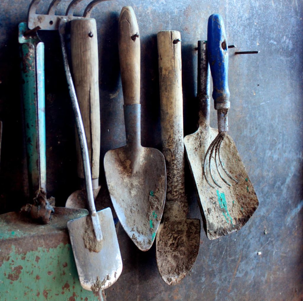 Dirty Garden Tools Hanging Up On Wall
