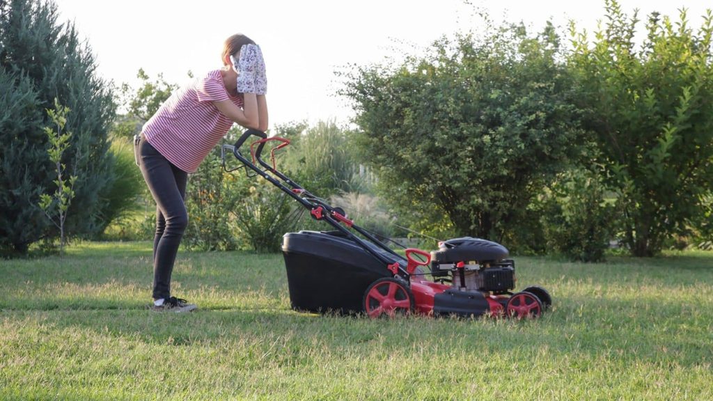frustrated woman mowing the grass with lawn mower